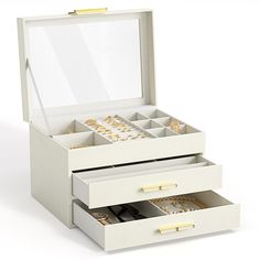 an open jewelry box with three drawers and two gold rings on the lid, sitting on a white surface