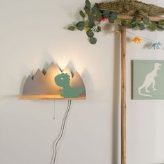 a light that is on the side of a wall next to a plant and some pictures