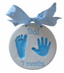 a white ornament with blue handprints and a bow on it that says todd 7 months