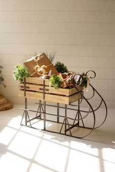 a wooden crate filled with vegetables sitting on top of a white floor next to a potted plant