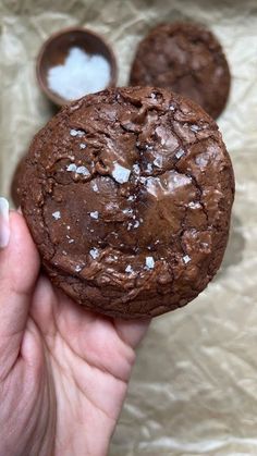 a person holding a chocolate cookie in their hand