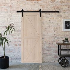 a living room with brick walls and a sliding barn door in the middle, next to a potted plant