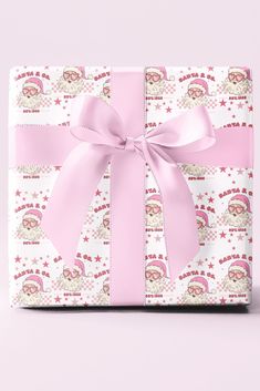 a present wrapped in pink and white paper with a bow on it's side