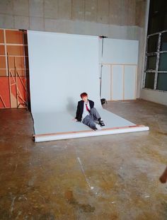 a man sitting on the ground in front of a white backdrop