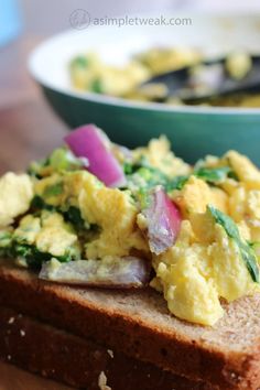 an egg salad on top of bread next to a bowl of soup in the background