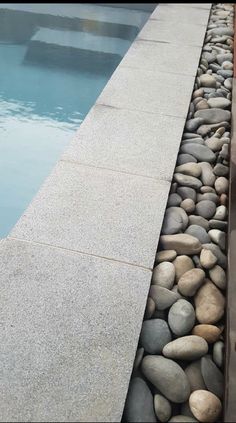 a long row of rocks next to a swimming pool