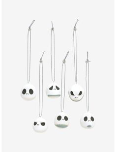 five different necklaces with faces on them hanging from chains, one is white and the other has black eyes