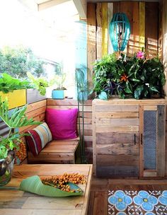 a wooden bench sitting next to a planter on top of a wooden floor covered in plants