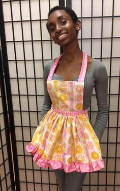 a woman wearing an apron standing in front of a wall