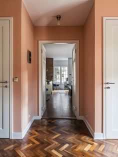 an empty hallway with wooden floors and orange walls, painted in pale pinks or browns