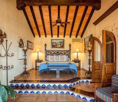 a living room filled with furniture and lots of wood beams on the ceiling, along with tile flooring