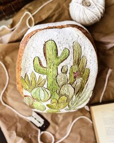 a rock with a cactus painted on it next to a crochet book and yarn