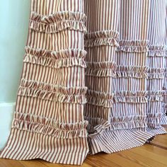 the curtains are striped with ruffles in brown and white colors on wood flooring