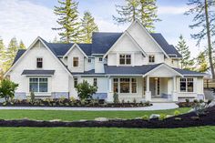 a large white house with lots of windows and grass in front of the house on a sunny day