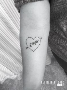 a heart with an arrow and the word love tattooed on it's arm, in black ink