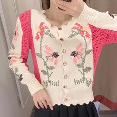 a woman taking a selfie in front of a mirror wearing a pink and white cardigan