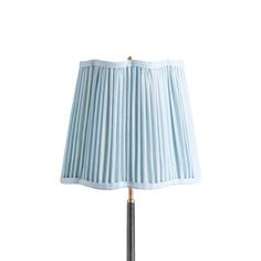 a lamp that is on top of a white surface with blue pleated lampshade