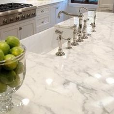 a bowl of green apples sitting on top of a kitchen counter next to a sink