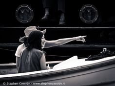 a woman pointing at something while sitting in a small boat with another person behind her