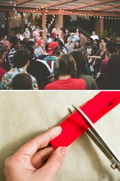 a hand holding a pair of scissors in front of a group of people at an event