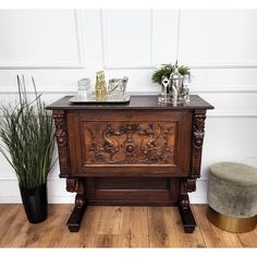 an old wooden cabinet sitting on top of a hard wood floor next to a potted plant