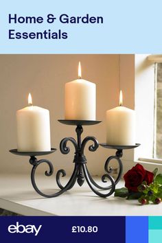 three candles are sitting on a window sill next to a rose and two roses