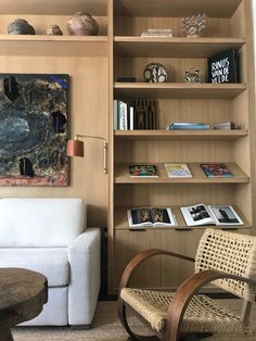 a living room filled with furniture and bookshelves next to a wall mounted painting