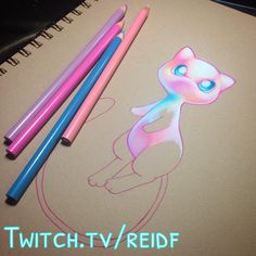 three colored pencils sitting next to each other on top of a notebook with a drawing of a cat