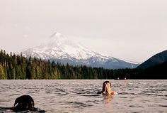 two people swimming in the water with a mountain in the backgroung behind them