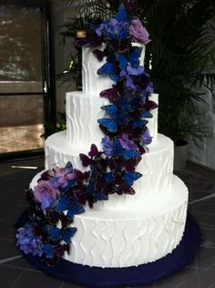 a wedding cake with purple and blue butterflies on it