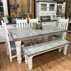 a kitchen table with two benches next to it on a hard wood floor in front of an oven