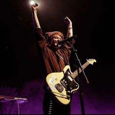 a man holding his guitar up in the air