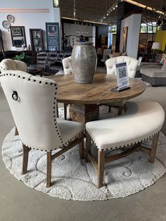 a round table with two chairs and a vase sitting on top of it in a store