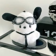 a white stuffed animal wearing goggles on top of a table next to a clock