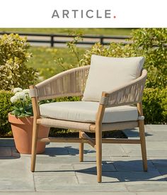 a chair sitting on top of a patio next to a potted plant and flowers