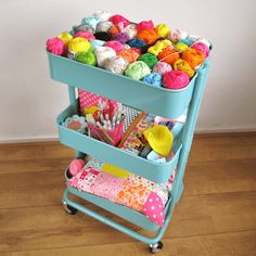 a blue cart filled with yarn and crochet on top of a hard wood floor