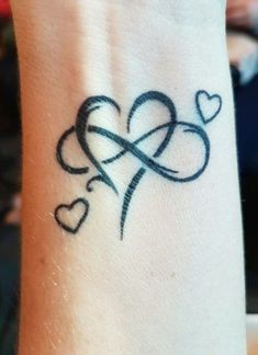 a tattoo on the wrist of a person with two hearts and an arrow in the middle