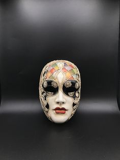 "Size: one size Traditional and original papier-mache Venetian mask, handmade and decorated with trimmings, stucco and acrylics. This traditional Venetian mask shape is called \"Volto mask\" and is a full face mask. This mask remembers Harlequin for the style of the decoration and its coloros. All our masks are handmade papier-machè masks, made in Venice. Our decorators use techniques typical of the Venetian tradition such as stucco, acrylics, gold and silver-leaf, macramè, passementerie, pearls Venetian Multicolor Masquerade Mask, Artistic Multicolor Masquerade Mask For Carnival, Artistic Multicolor Masquerade Mask For Mardi Gras, Artistic Multicolor Masquerade Masks, Artistic Multicolor Masks For Masquerade, Artistic Multicolor Masks For Carnival, Multicolor Full Face Carnival Mask, Volto Mask, Venice Mask