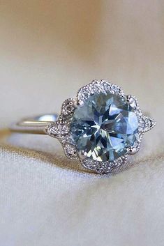 a blue diamond ring sitting on top of a white cloth