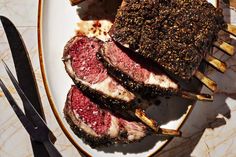 some meat is on a white plate with utensils and a fork next to it