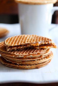 a stack of waffles sitting on top of a white plate next to a cup