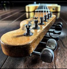 a close up of an electric guitar's neck and frets on a wooden floor