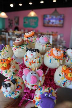 a hand holding a bunch of cake pops covered in frosting and sprinkles