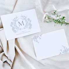 two cards with the letter m on them are laying next to each other and some flowers