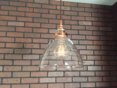 a clear glass light hanging from a brick wall