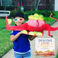 a young boy holding up a paper dragon