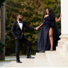 a man in a tuxedo is holding the hand of a woman in a black dress