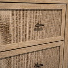 a close up of a wooden dresser with wicker drawers and knobs on it