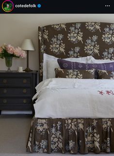 a bed with flowers on the headboard and two nightstands in front of it