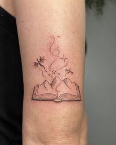 a woman's arm with a book and stars tattoo on her left side ribcage